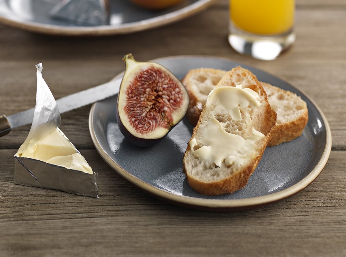 Image of foil-wrapped cheese with fruit and bread on a plate